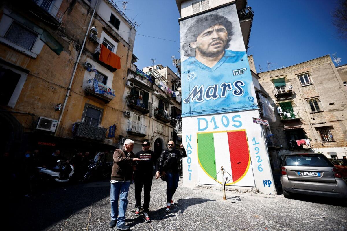 People walk past a mural depicting late Argentinian football legend Diego Maradona. — Reuters