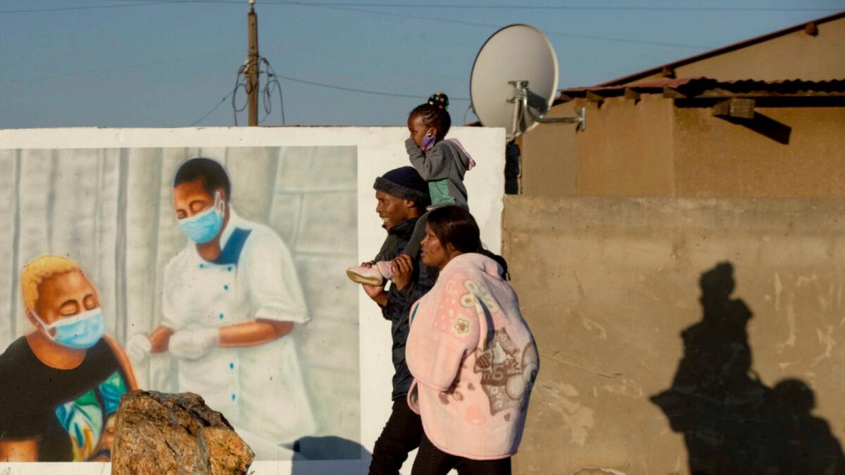 A family walks past a mural promoting vaccination for Covid-19 in Duduza township, east of Johannesburg. In the entire African continent, less than three per cent received a single dose of vaccine. — AP file