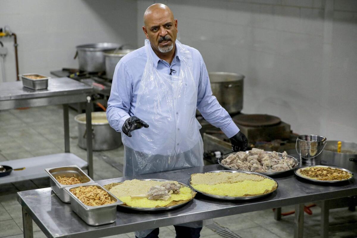 Ashraf al-Mubaideen, co-owner of a traditional restaurant specialising in the traditional Jordanian dish 'Mansaf', speaks as he prepares a meal at the kitchen in Amman on March 16, 2023. — AFP