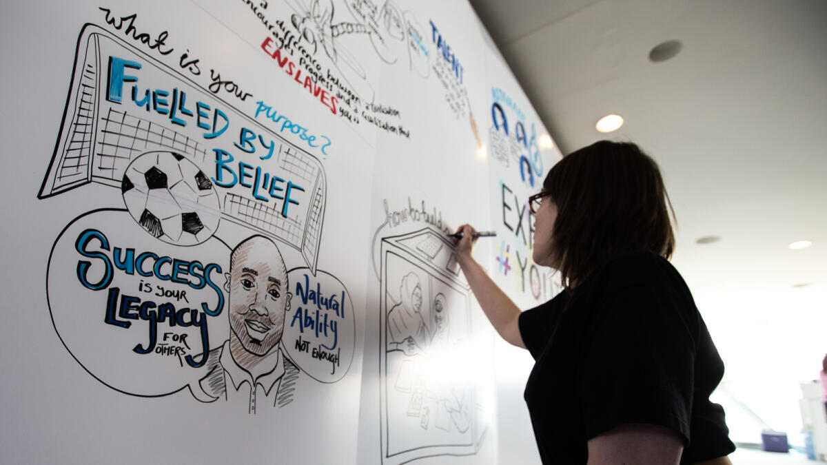 An artist drawing at a wall at the Youth Connect Forum at Meydan.