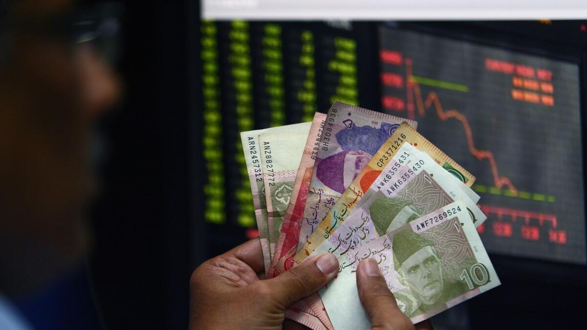 A man holds Pakistan rupees in Dubai. Falling foreign exchange reserve will also put pressure on the rupee, which lost around 3.9 per cent last month. — File photo