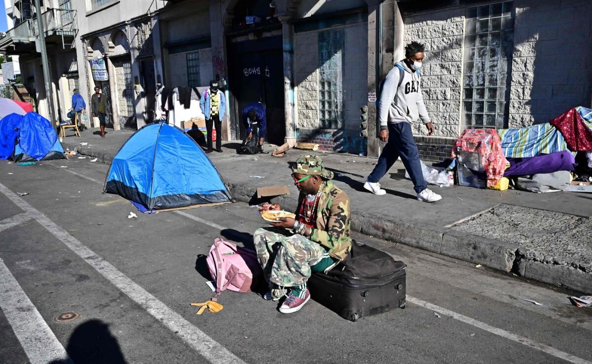 A homeless man sits on a luggage bag along a downtown Los Angeles street lined with tents housing the homeless on November 22, 2023 in Los Angeles, California, where skyrocketing rents in recent years has led to an increasing rise in the number of unhoused people.  — AFP file