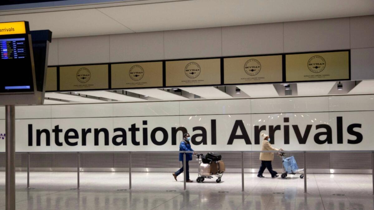 Passengers walk past a sign in the arrivals area at Heathrow Airport in London. — AP file