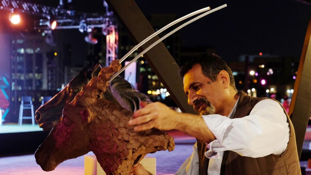 Ramy Ragheb, an artist poses next to one of his sculpture during the Al Shindagha Days festival.
