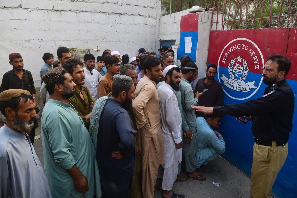 refugees queue outside a police station for their data verification by the National Database and Registration Authority (NADRA) in Karachi on November 8, 2023. — AFP