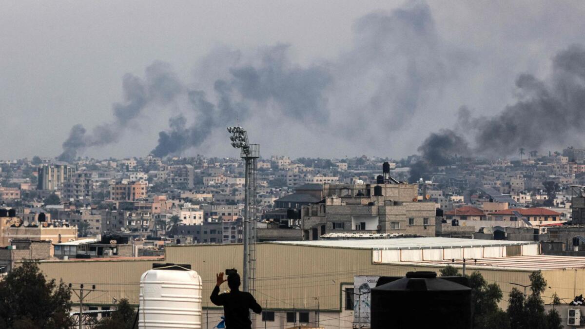 A man takes pictures from a rooftop as smoke billows over Khan Yunis in the southern Gaza strip during Israeli bombardment. — AFP