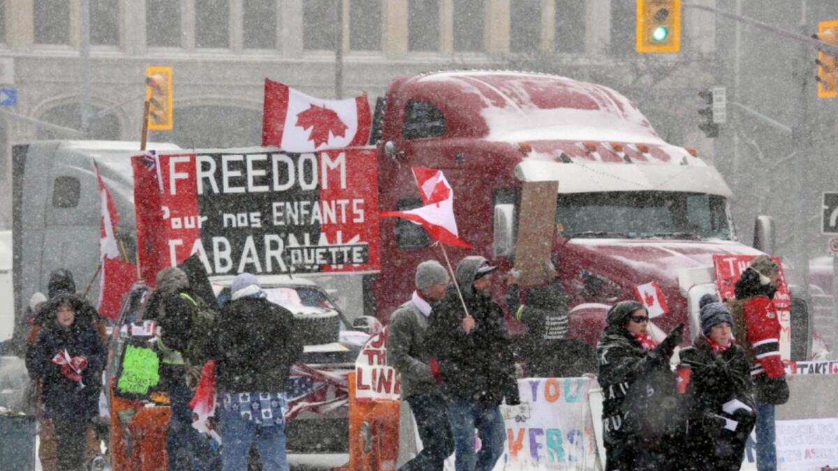 Protesters and supporters walk pass parked trucks on Wellington street as demonstrators continue to protest the Covid-19 mandate in Ottawa. — AFP