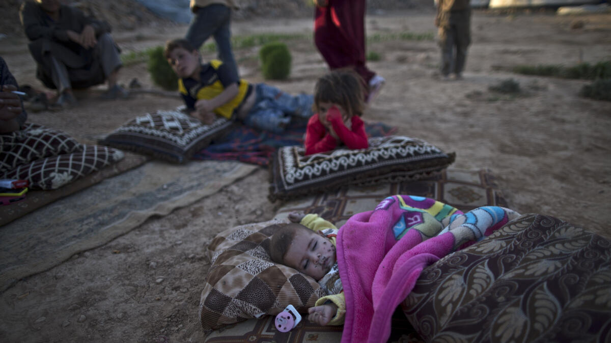 Four-month-old Marwa, face covered with flies, sleeps on the ground outside her family’s tent.
