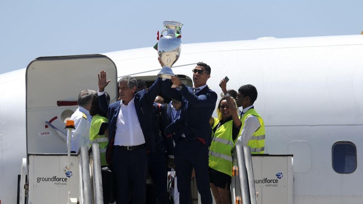 Portugal's Cristiano Ronaldo and coach Fernando Santos, left, lifts the Euro 2016 trophy after defeating France in the final, as they arrive at the Humberto Delgado Airport in Lisbon, Portugal,on  Monday.
