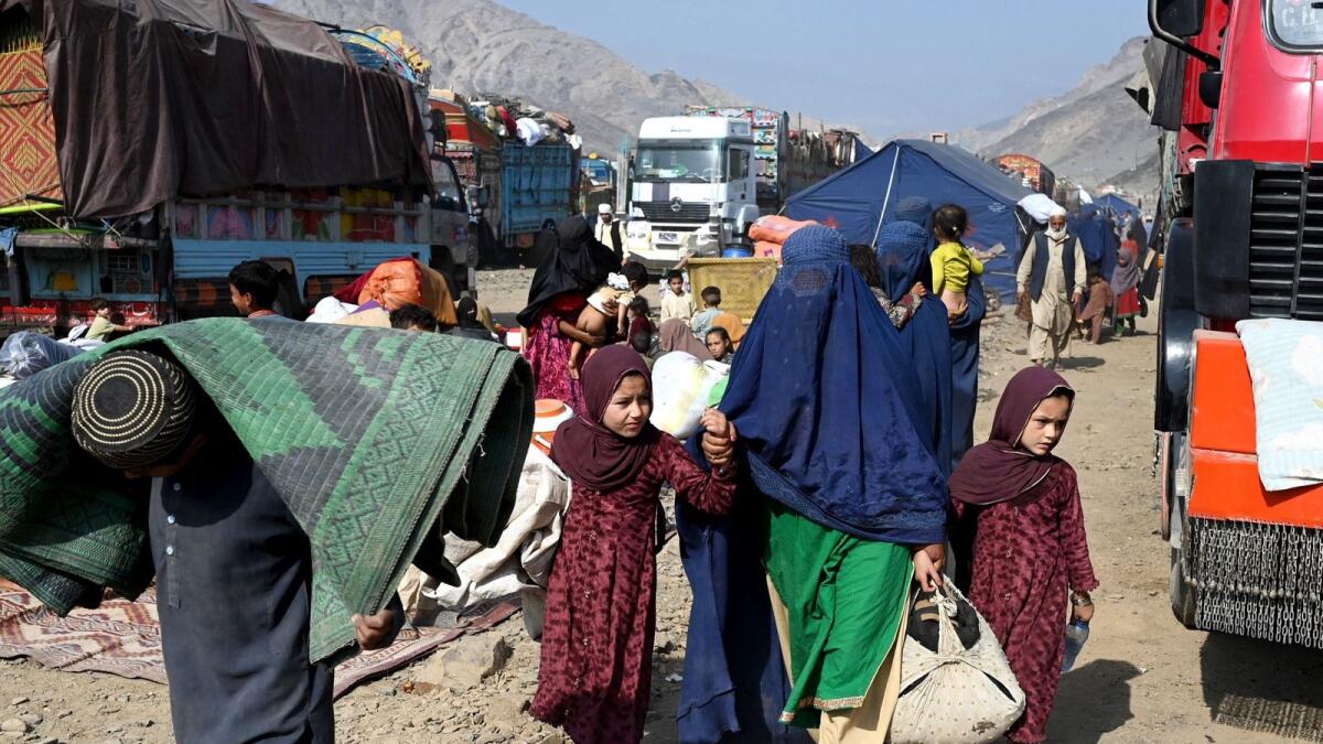 Afghan refugees carry their belongings upon their arrival from Pakistan, at a makeshift camp near the Afghanistan-Pakistan Torkham border in Nangarhar province on November 2, 2023. More than 165,000 Afghans have fled Pakistan in the month since its government ordered 1.7 million people to leave or face arrest and deportation, officials said on November 2. (Photo by Wakil KOHSAR / AFP)