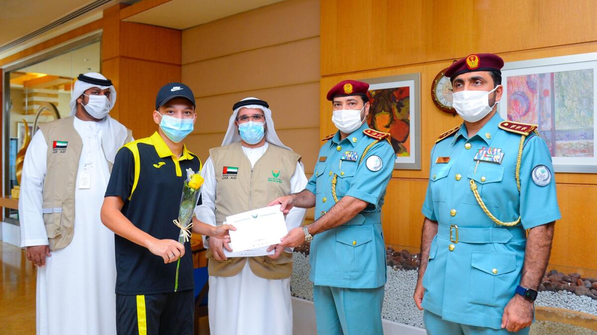 The Sharjah Police presents one of the stranded residents with a return ticket home and a rose. — Supplied photo 