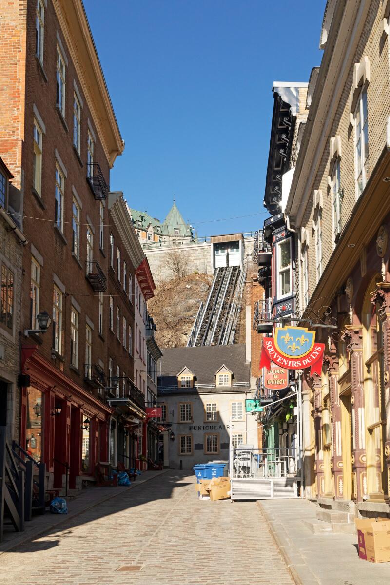 Souvenir stores and cafes on Rue Sous-le-Fort in the Lower Town of Quebec City, Canada. The Old Quebec Funicular (Funiculaire du Vieux-Québec) operates from the house at the end of the street.