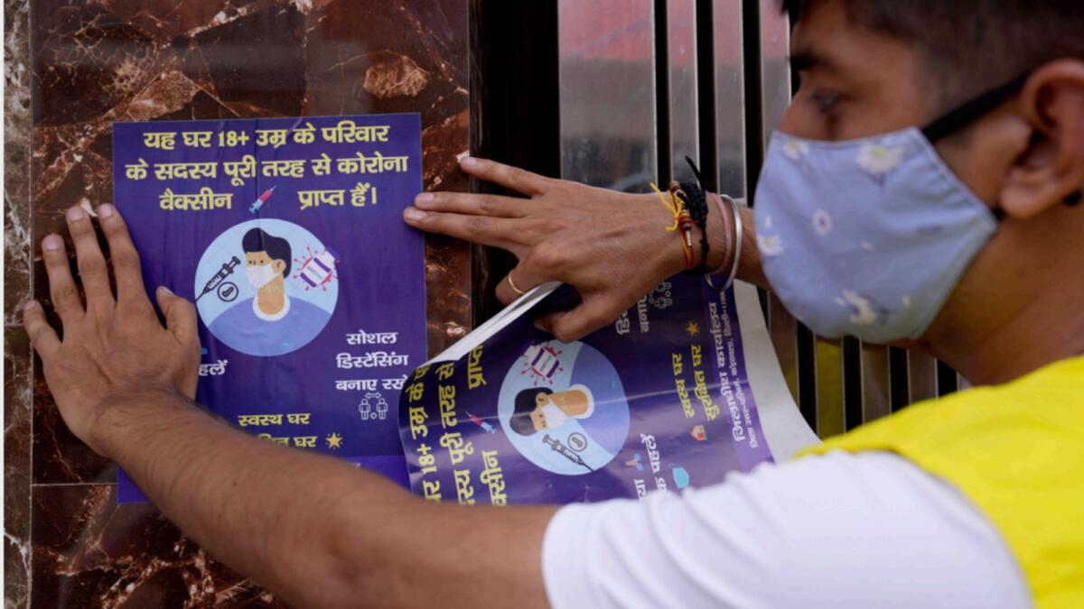 A volunteer near New Delhi pastes a poster informing that all adult members of this house are fully vaccinated for Covid-19. — AP