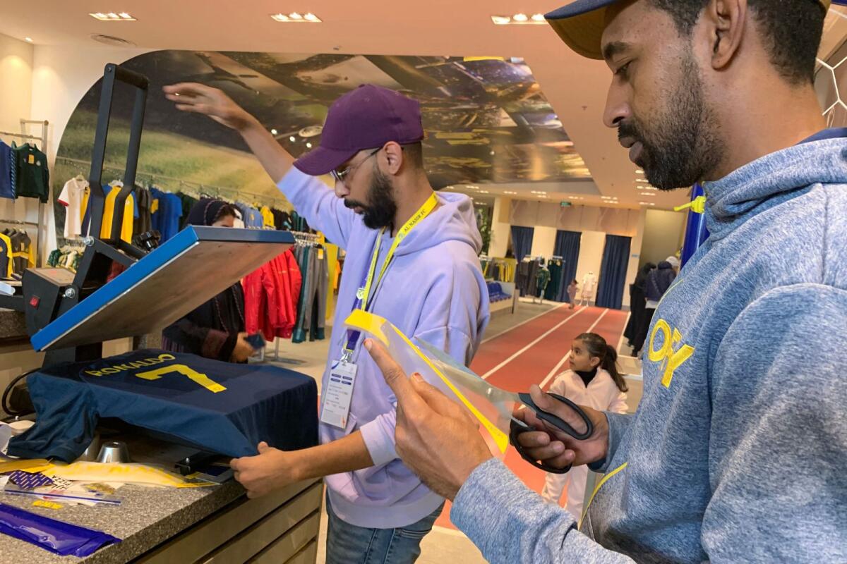 An employee at the Saudi Al Nassr FC shop prepares a t-shirt marked Ronaldo and number 7, in the Saudi capital Ryadh, on December 31, 2022. — AFP