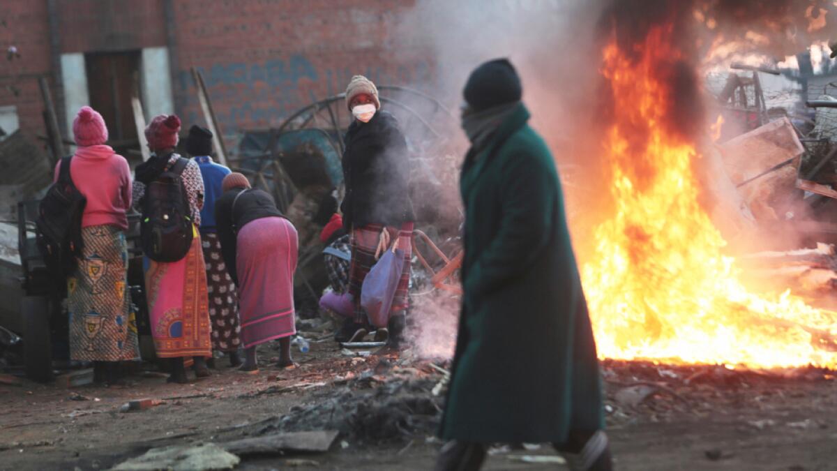 A man walks past a burning fire in a poor neighborhood in Harare. Zimbabwe’s  finance minister says the country's economy is expected to shrink by 4.5% this year, although others say it will contract even more, as the effects of the coronavirus and a drought take a toll on the struggling southern African nation. Photo: AP