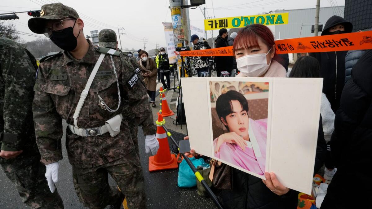 A fan waits for K-pop band BTS's member Jin to arrive before he enters the army to serve near an army training center in Yeoncheon, South Korea, Tuesday, December 13.