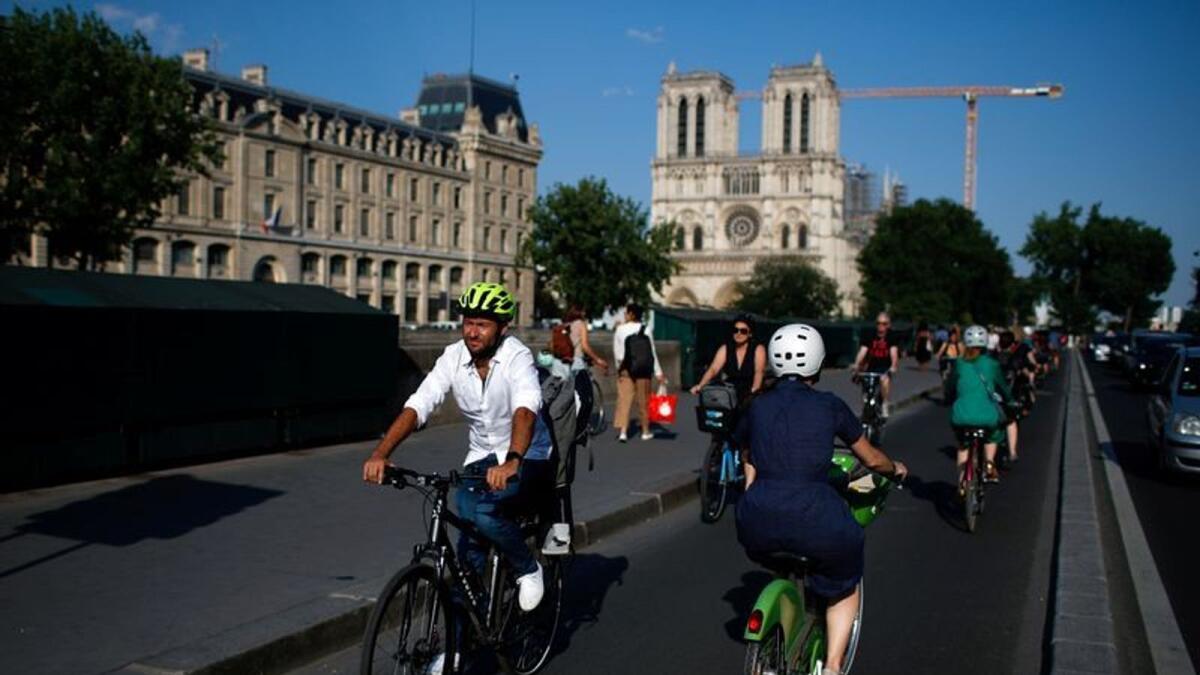 People ride bicycles near Notre Dame Cathedral during a warm and sunny day in Paris as a heatwave hits France, June 25, 2020.