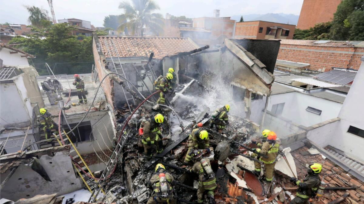 Firefighters work at the crash site of a small plane that fell on top of homes in a residential area of Medellin. — AP