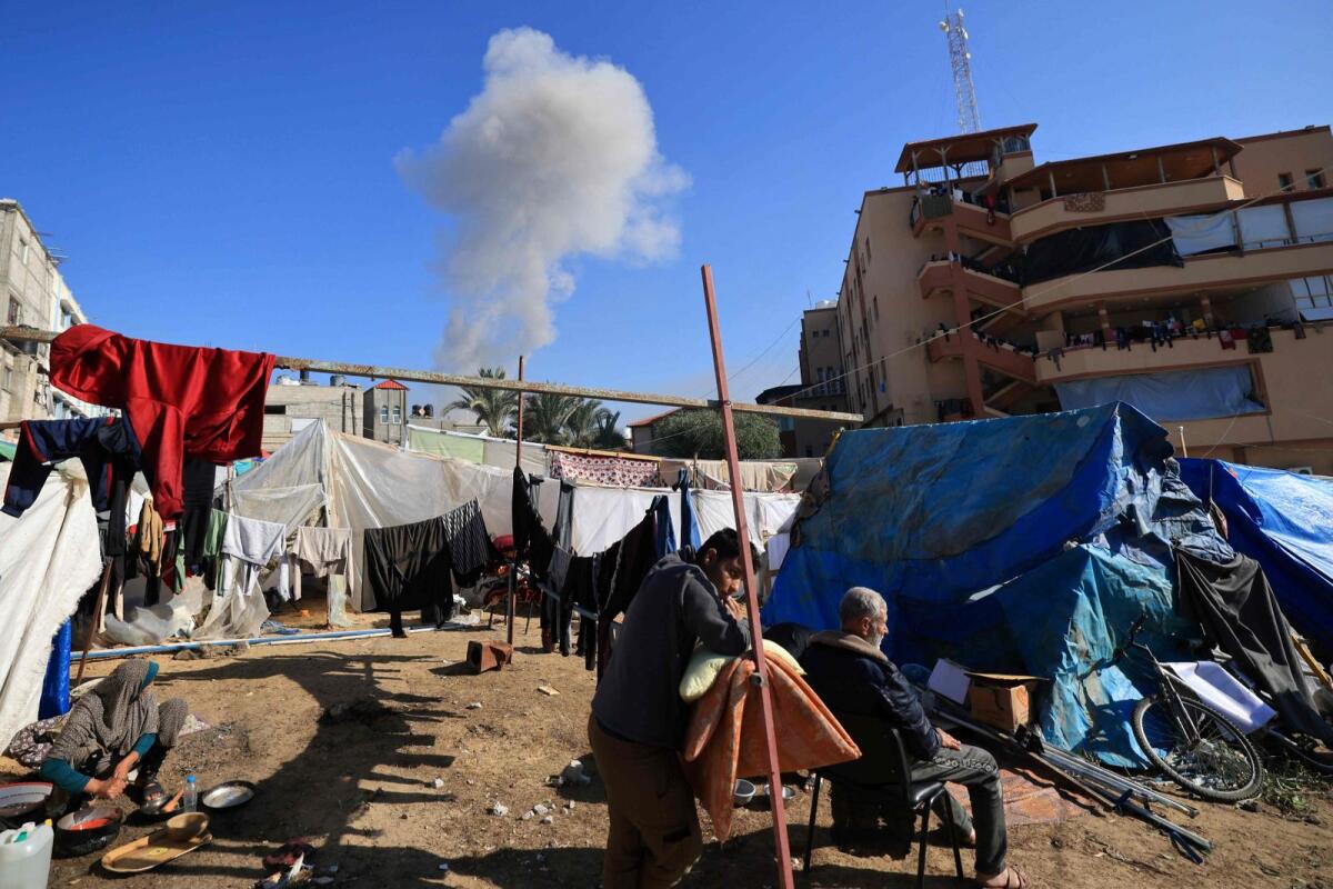 People gather near tents used as temporary shelter as smoke rises during an Israeli strike on Khan Yunis in the southern Gaza Strip on Thursday. — AFP