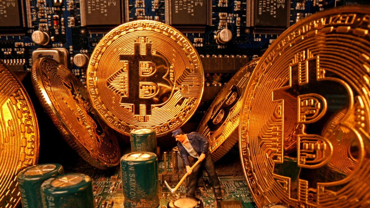 A small toy figure and representations of the virtual currency Bitcoin stand on a motherboard in this picture. — Reuters