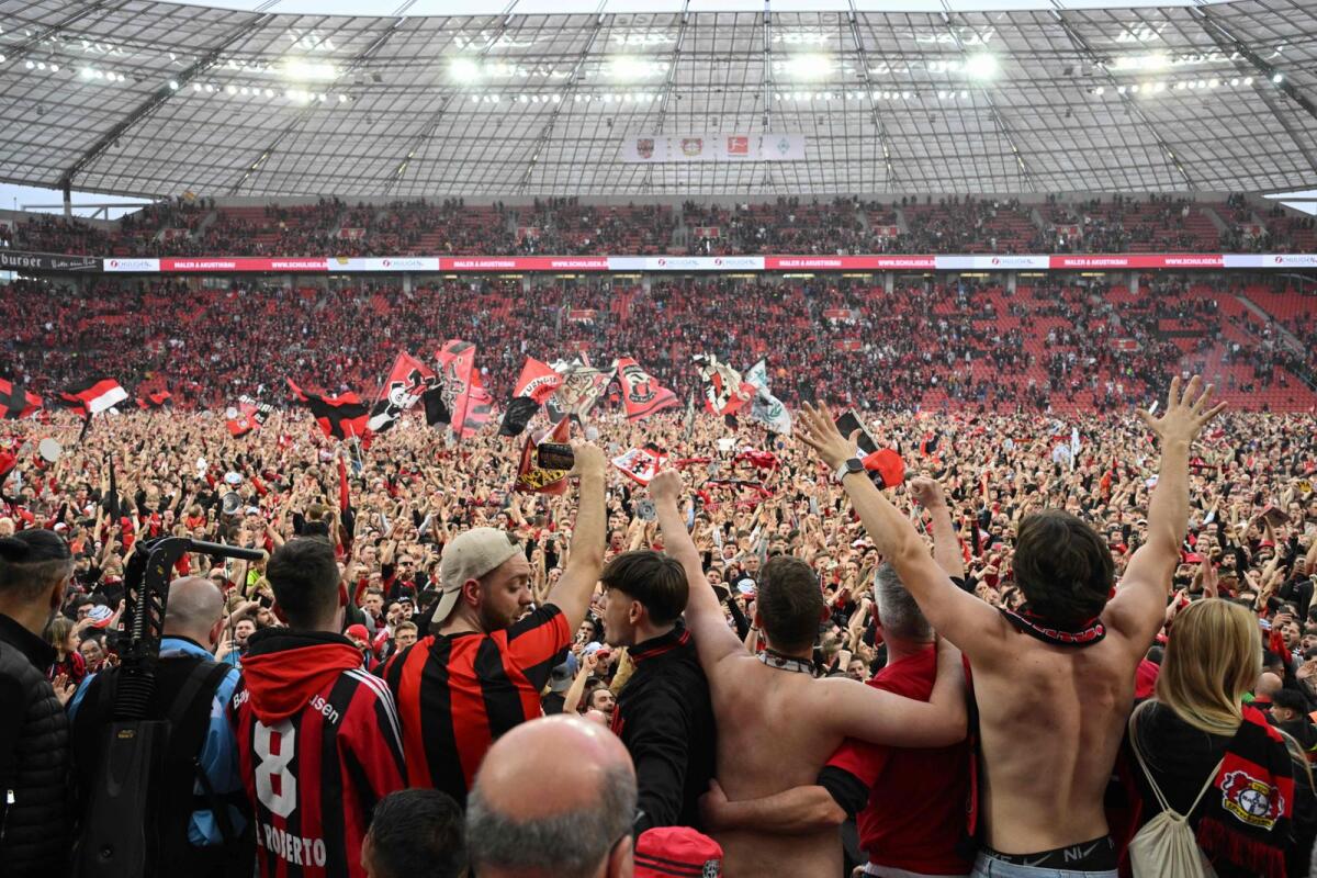 Leverkusen fans celebrate on the pitch after the team won their first ever German first division title. — AFP