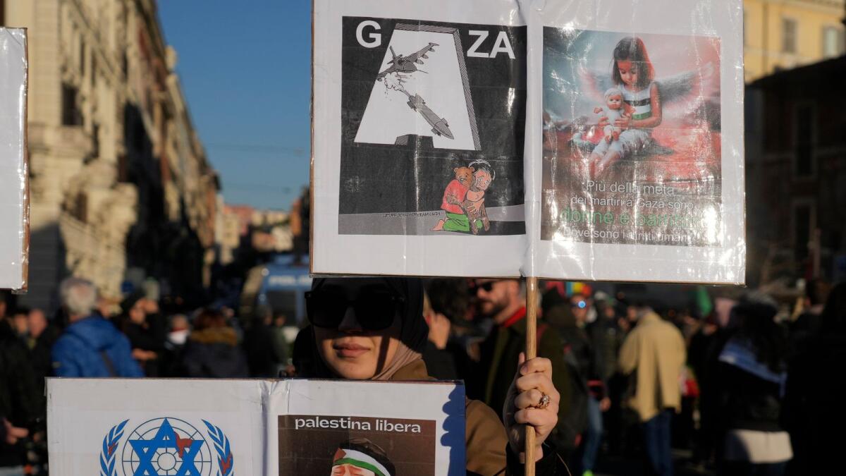 A woman holds placards, reading, bottom right: 'Free Palestine, and top right: More than half of the martyrs in Gaza are women and children. Where are the human rights', during a rally in support of the Palestinians in Rome, Saturday, Jan. 13, 2024. AP