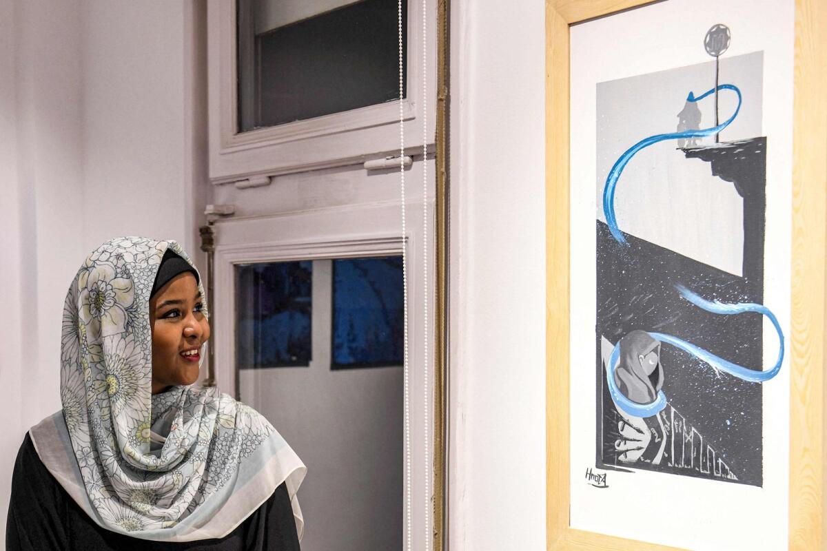 Sudanese visual artist Fatima Ismail looks at one of her creations during an exhibition organised by Sudanese artists at the Goethe institute in the Egyptian capital Cairo on November 26, 2023.  — AFP