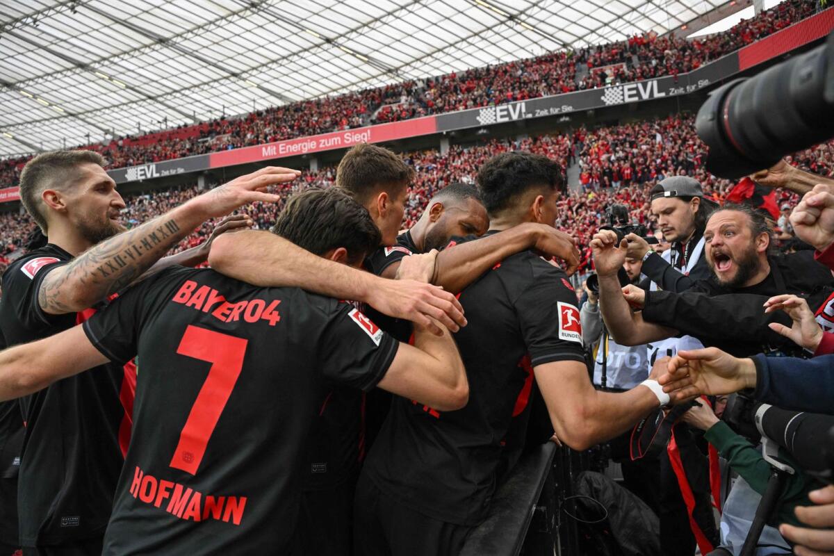 Bayer Leverkusen players celebrate their third goal with fans. — AFP
