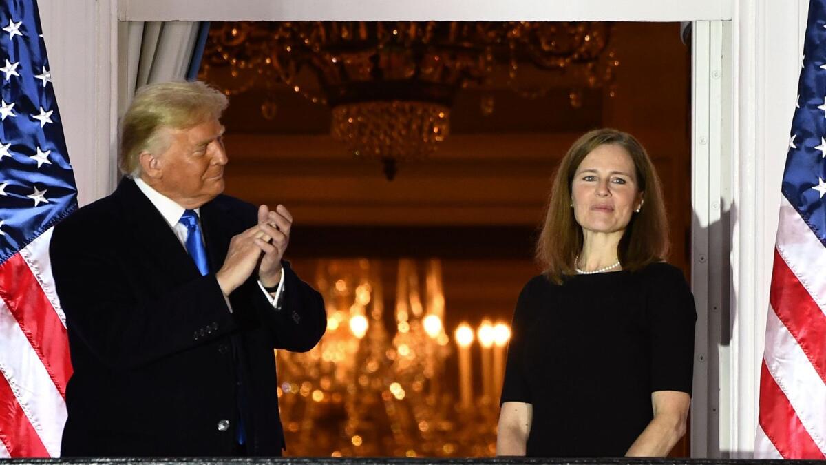 US President Donald Trump applauds Judge Amy Coney Barrett after she was sworn in as a US Supreme Court Associate Justice during a ceremony on the South Lawn of the White House.  AFP