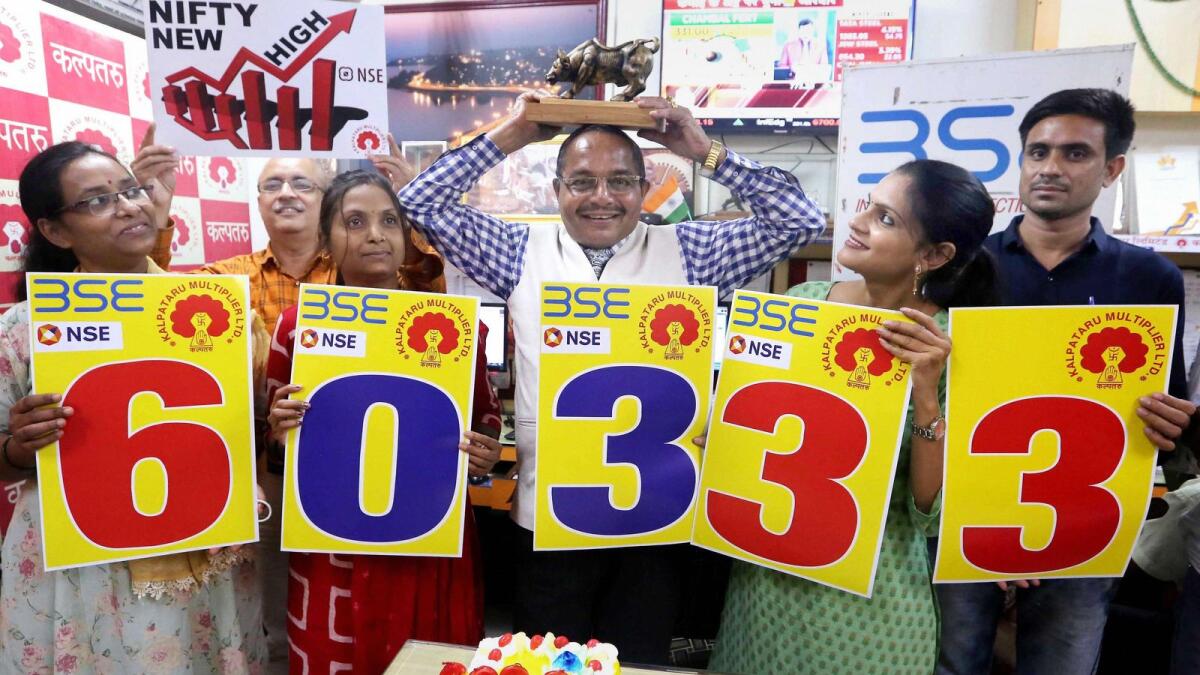Investors and share brokers celebrate at a share terminal after the Bombay Stock Exchange (BSE) Sensex Index reached the record 60,333 mark in an intra-trade session, in Bhopal on Friday. — PTI
