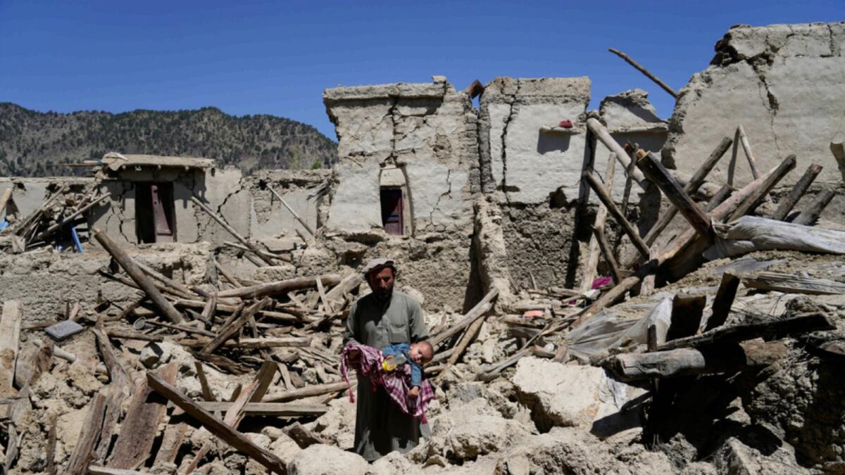 A man carries his child amid destruction after an earthquake in Gayan village, in Paktika province, Afghanistan. — AP