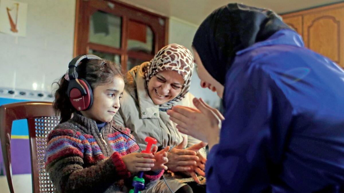 Syrian refugee Aya Al Souqi, left, smiles  during her first hearing test by Zaineb Abdulla, right, vice-president of  Deaf Planet Soul, a Chicago hearing charity, at Joub Jannine village in the Bekaa valley. 