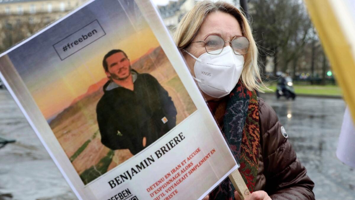A woman holds a photo of Benjamin Briere during a rally in Paris. — AP file
