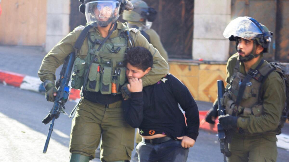 Israeli soldiers detain a Palestinian boy during clashes in Hebron, in the Israeli-occupied West Bank. — Reuters