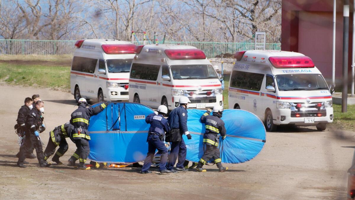 Firefighters and police officers transport rescued people from the missing tour boat 'Kazu 1' from Japanese Self-Defence Force's helicopters. (Reuters)