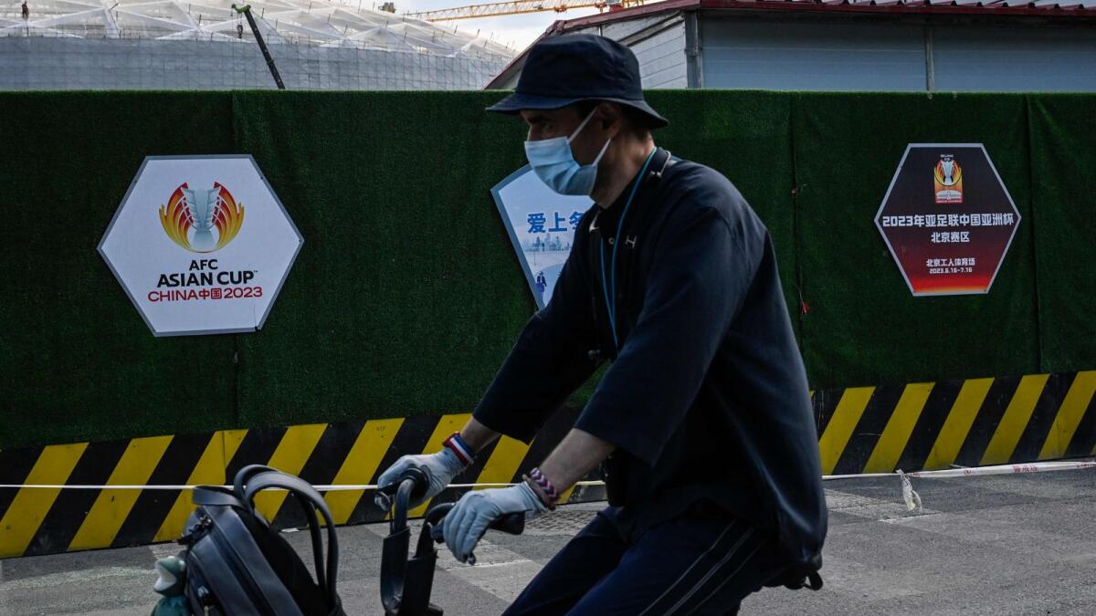 A man cycles past the construction site of the Workers' Stadium, a planned venue of the 2023 Asian Cup, in Beijing on Saturday. China has withdrawn as the 2023 Asian Cup host due to Covid-19 pandemic. (AFP)