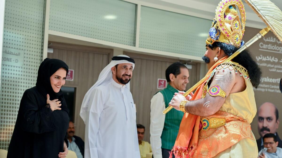 A staff member dressed as Mahabali greets Mohammed Ahmed Al Yamahi and Naema Al Sharhan.