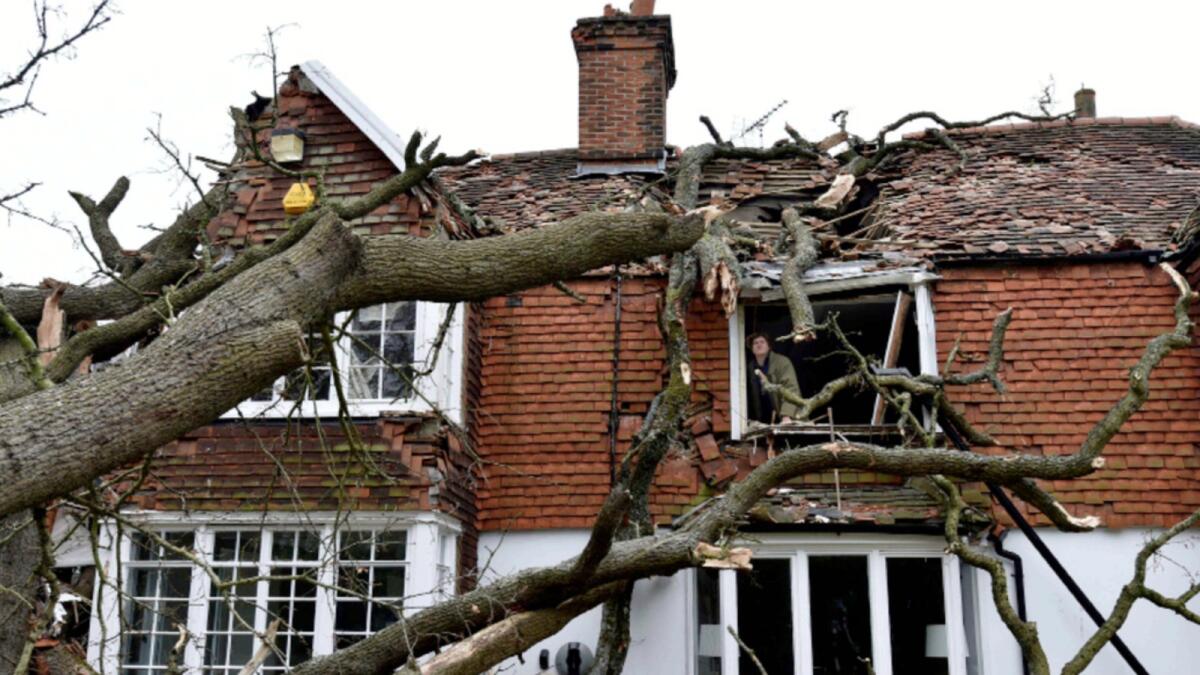 Sven Good, 23, looks out from his bedroom window at the damage caused to the family home a day after a 400-year-old oak tree in the garden was uprooted by Storm Eunice, in Stondon Massey, near Brentwood, Essex, England. — AP