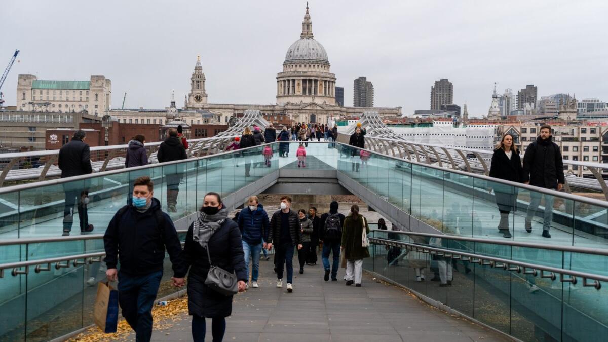Pedestrians walk across the Millennium Bridge across the River Thames with St Paul's Cathedral in the background in central London on December 11, 2021. Photo: AFP