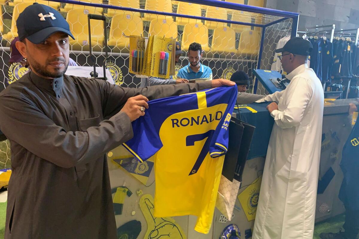 A fan holds t-shirt bearing the name Ronaldo and number 7, at the Saudi Al Nassr FC shop in the Saudi capital Ryadh, on December 31, 2022.  — AFP