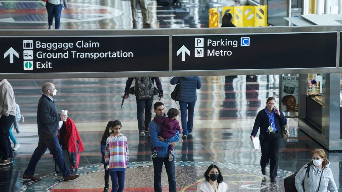 A mix of masked and unmasked travellers make their way through Ronald Reagan Washington National Airport. — Reuters file