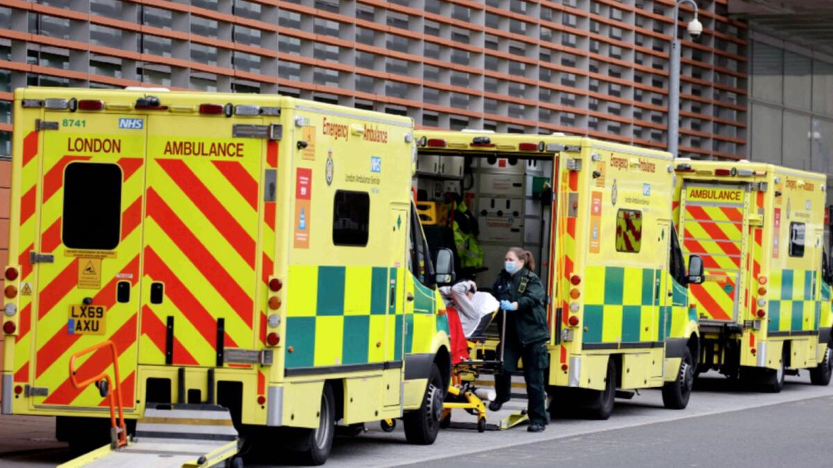 Paramedics unload a patient from the back of an ambulance parked outside the Royal London hospital in London. — AFP