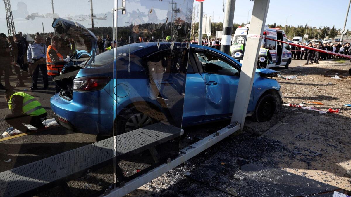 Israelis rescue personnel work next to the car on the scene where a suspected ramming attack took place in Jerusalem on Friday. — Reuters