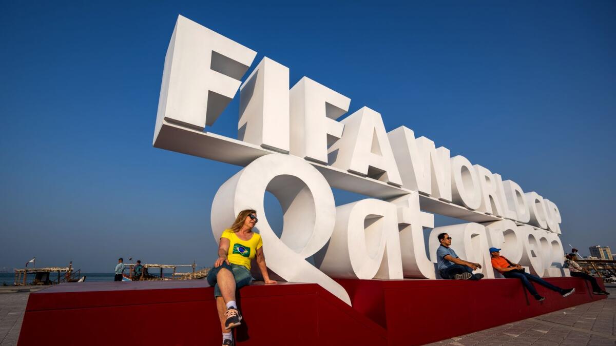 Visitors pose for photos with a Fifa World Cup sign in Doha. — AFP