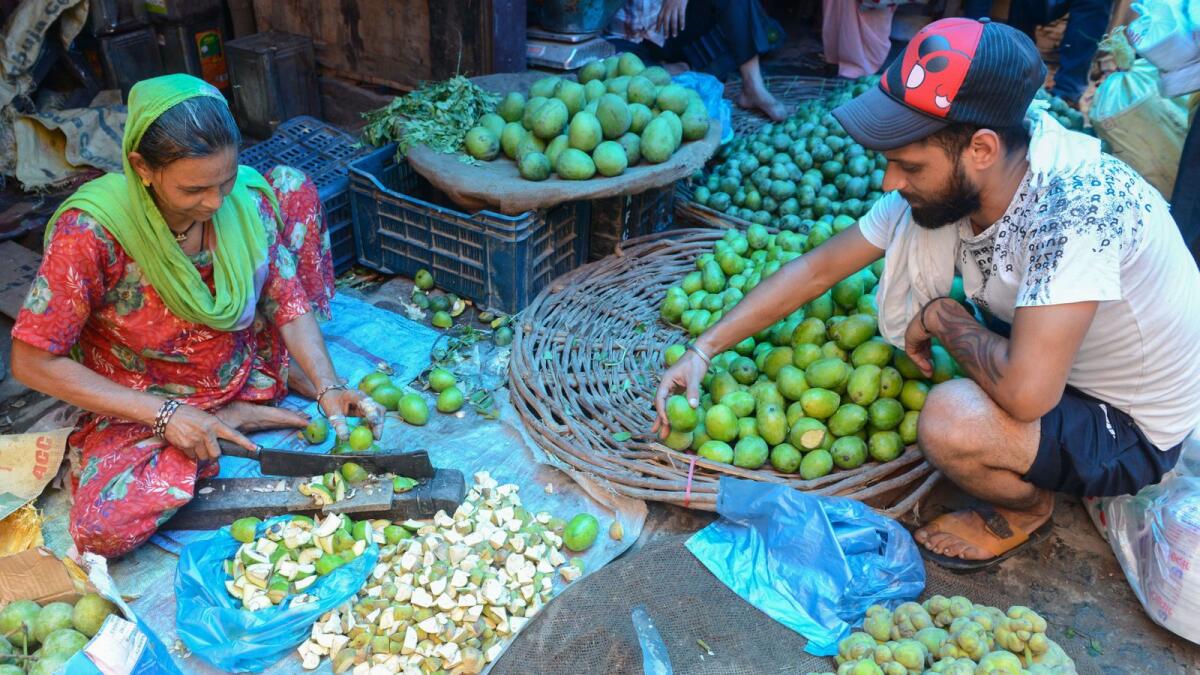 An Indian labourer cuts raw mangoes to be pickled at a vegetable market of Amritsar. The country's poor and middle class were taxed more than the rich, according to Oxfam report.