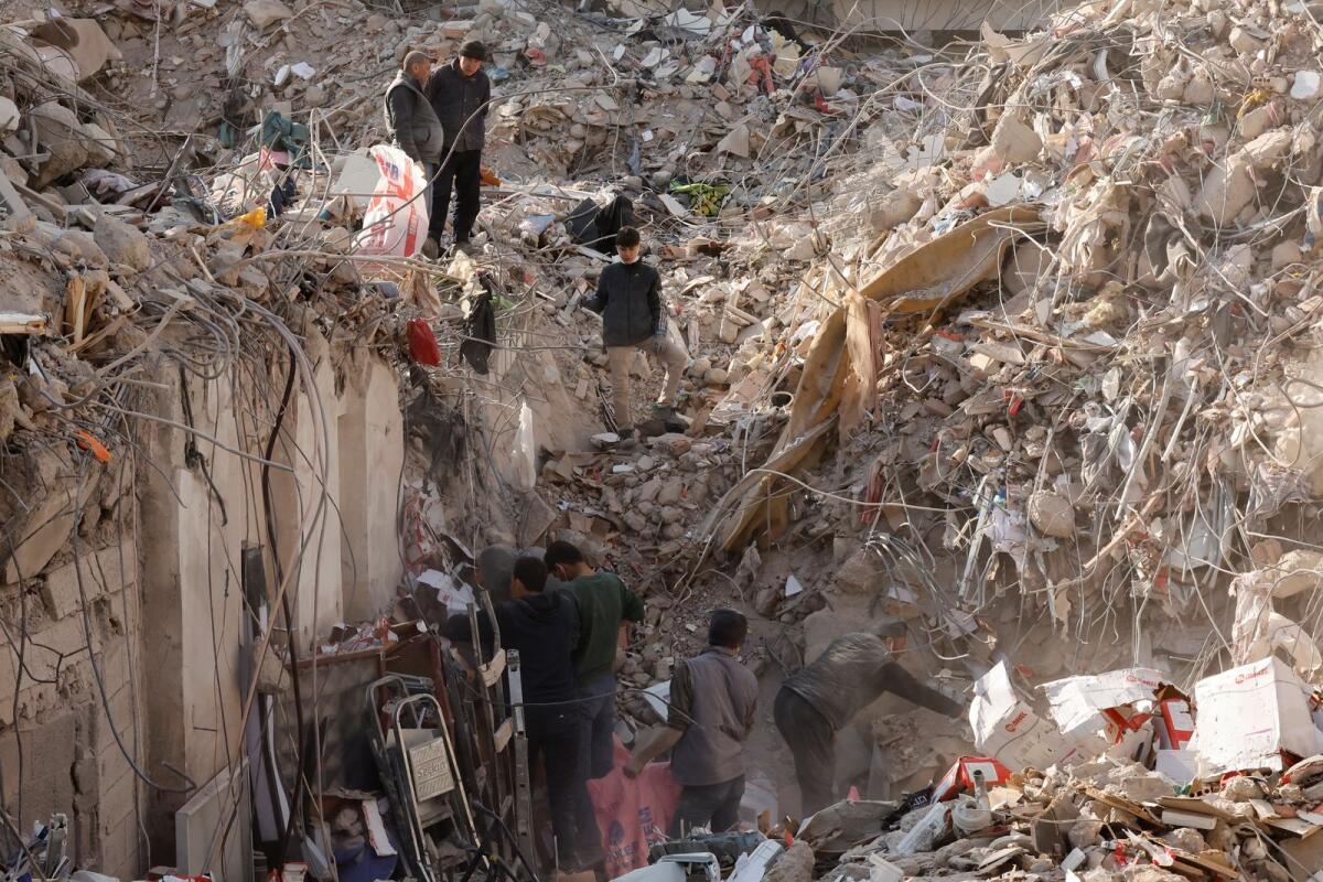 A family search their collapsed home for personal belongings in the rubble, in the aftermath of a deadly earthquake, in Kahramanmaras, Turkey, February 18, 2023. REUTERS/Clodagh Kilcoyne