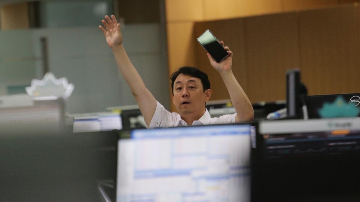 A currency trader gestures at the foreign exchange dealing room of the KEB Hana Bank headquarters in Seoul, South Korea on Thursday. Asian stock markets followed Wall Street higher following gains for major US tech stocks. - AP