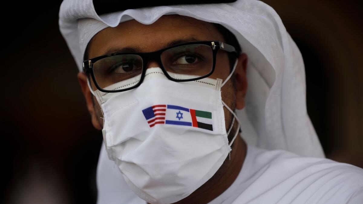 A man wearing a mask bearing the national flags of the UAE, America and Israel looks on after an Israeli flag carrier El Al airliner carrying Israeli and American delegates landed in Abu Dhabi. Photo: Reuters