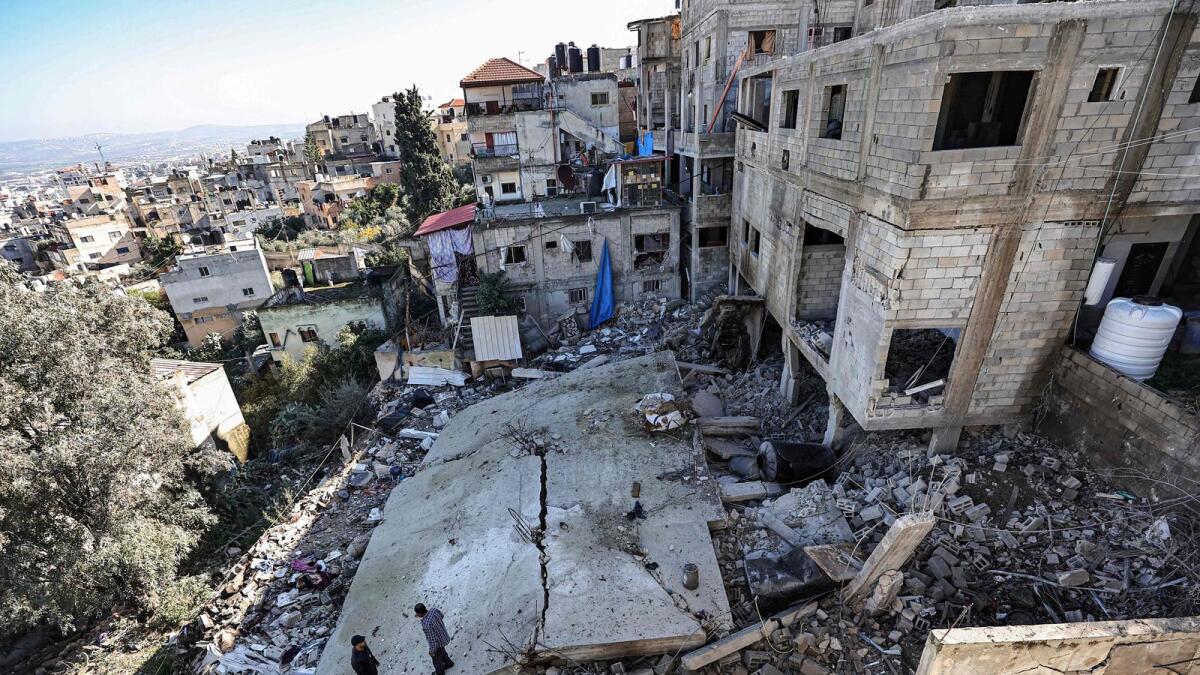 Men stand amid the rubble of a building destroyed during an Israeli army operation in the Jenin refugee camp. — AFP