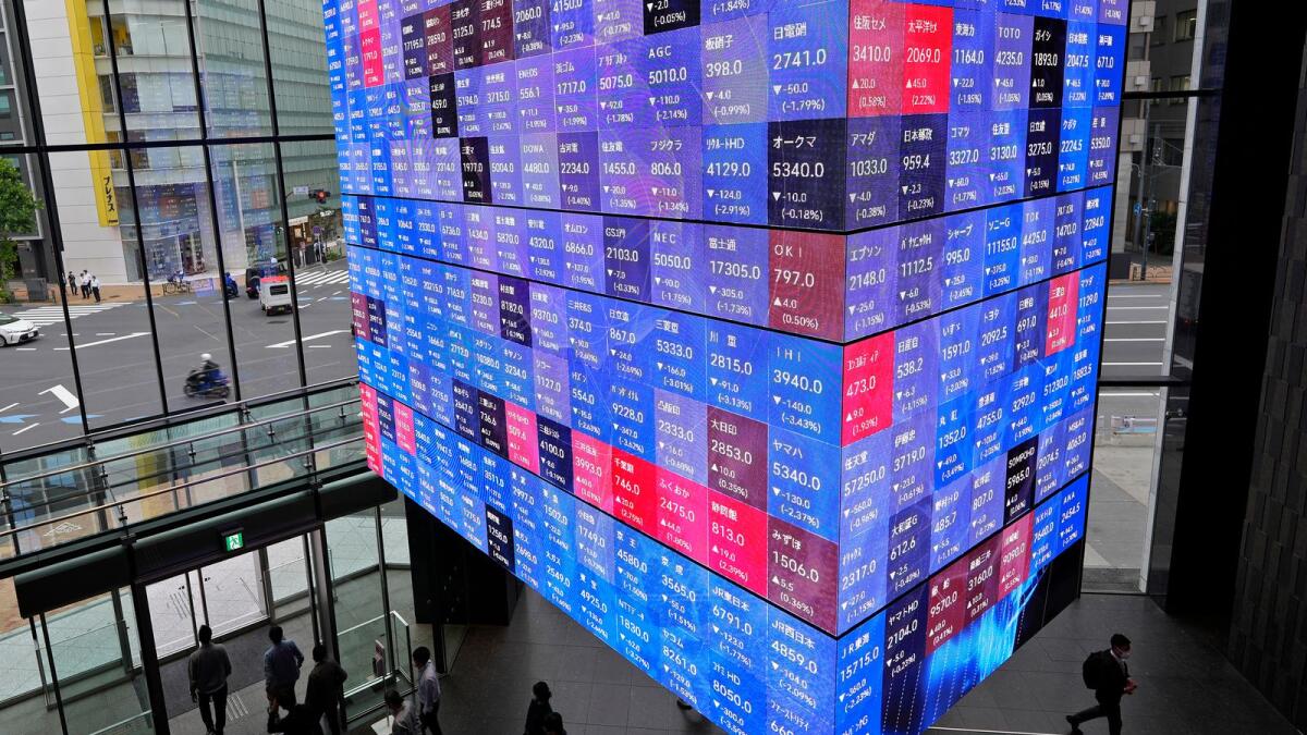 People walk under an electronic stock board showing Japan's stock prices in Tokyo. — AP